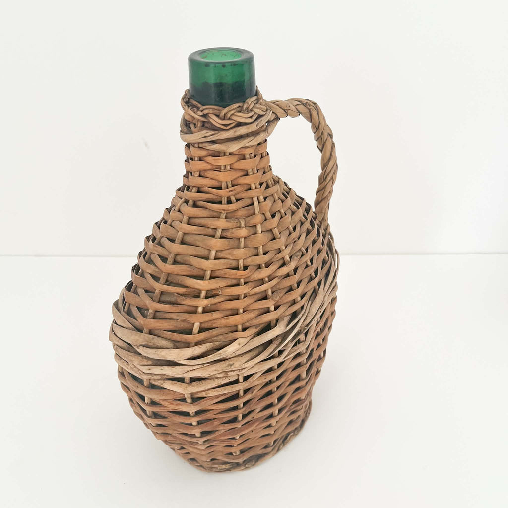 Beautiful vintage European wicker demijohn with natural brown willow weaving, a distinctive flattened oval shape and authentic rustic charm.