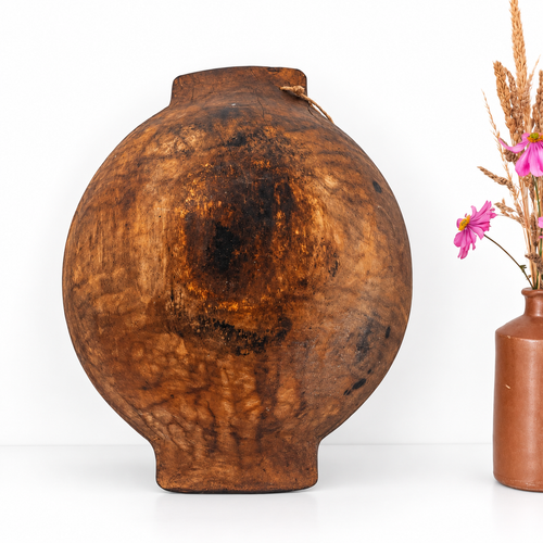 Back view of an antique European wooden dough bowl showing natural wood grain, weathered dark brown patina and traditional round shape with handles