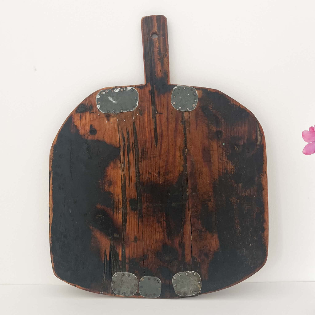 Antique European wooden bread board, hand-carved from solid wood with rounded corners, rustic patina and original metal repairs