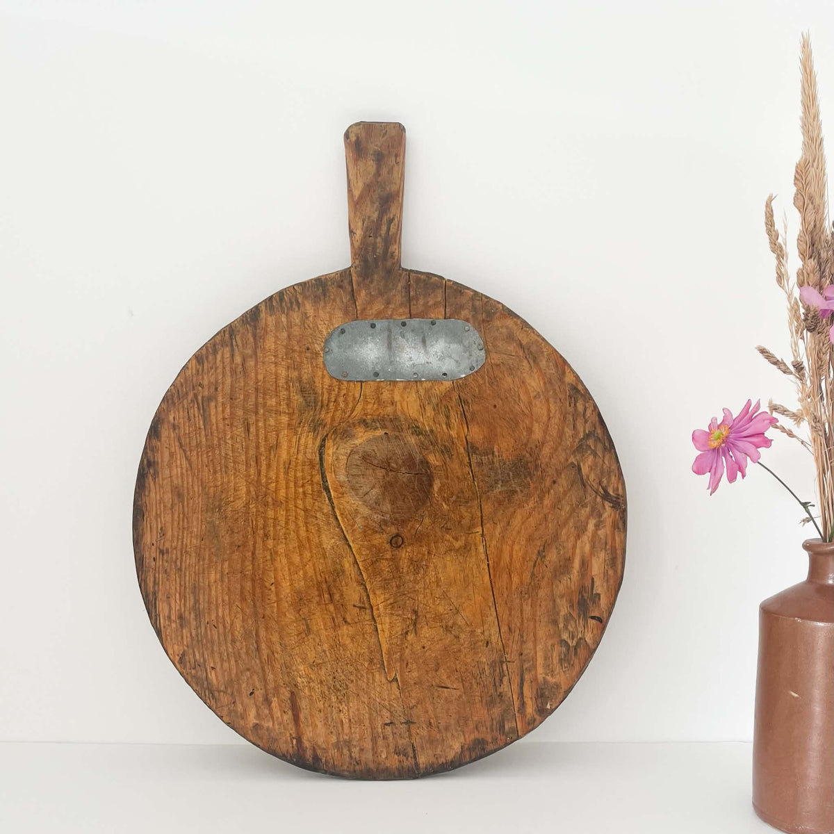Antique round wooden bread board with rustic patina, hand-carved from solid wood, perfect for farmhouse kitchen decor.