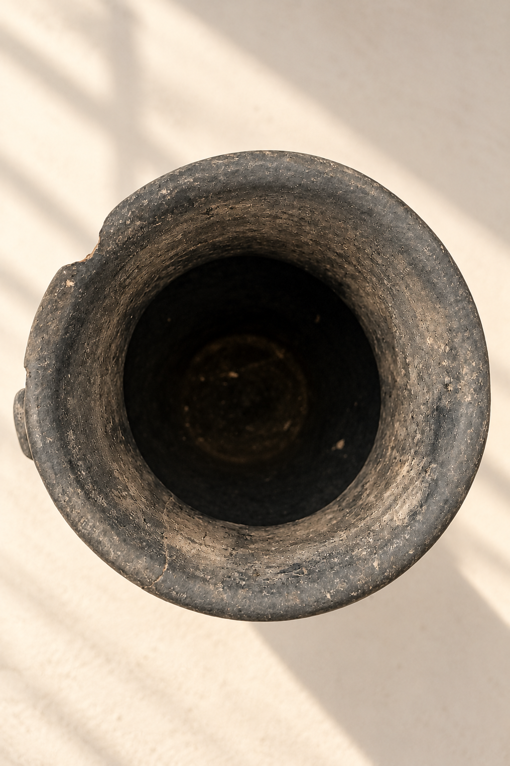 Top view of an antique terracotta vessel showing its circular opening, dark interior and aged clay rim