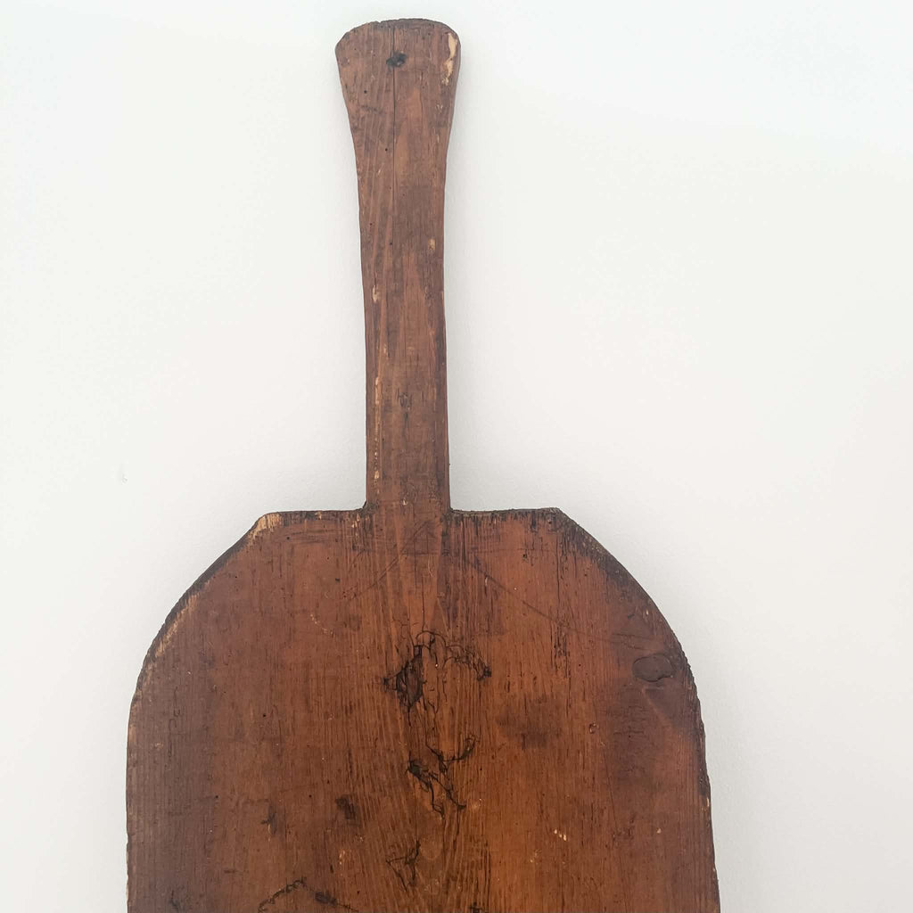 Antique wooden baker's paddle with an oval board and long narrow handle, featuring natural wood grain and vintage wear