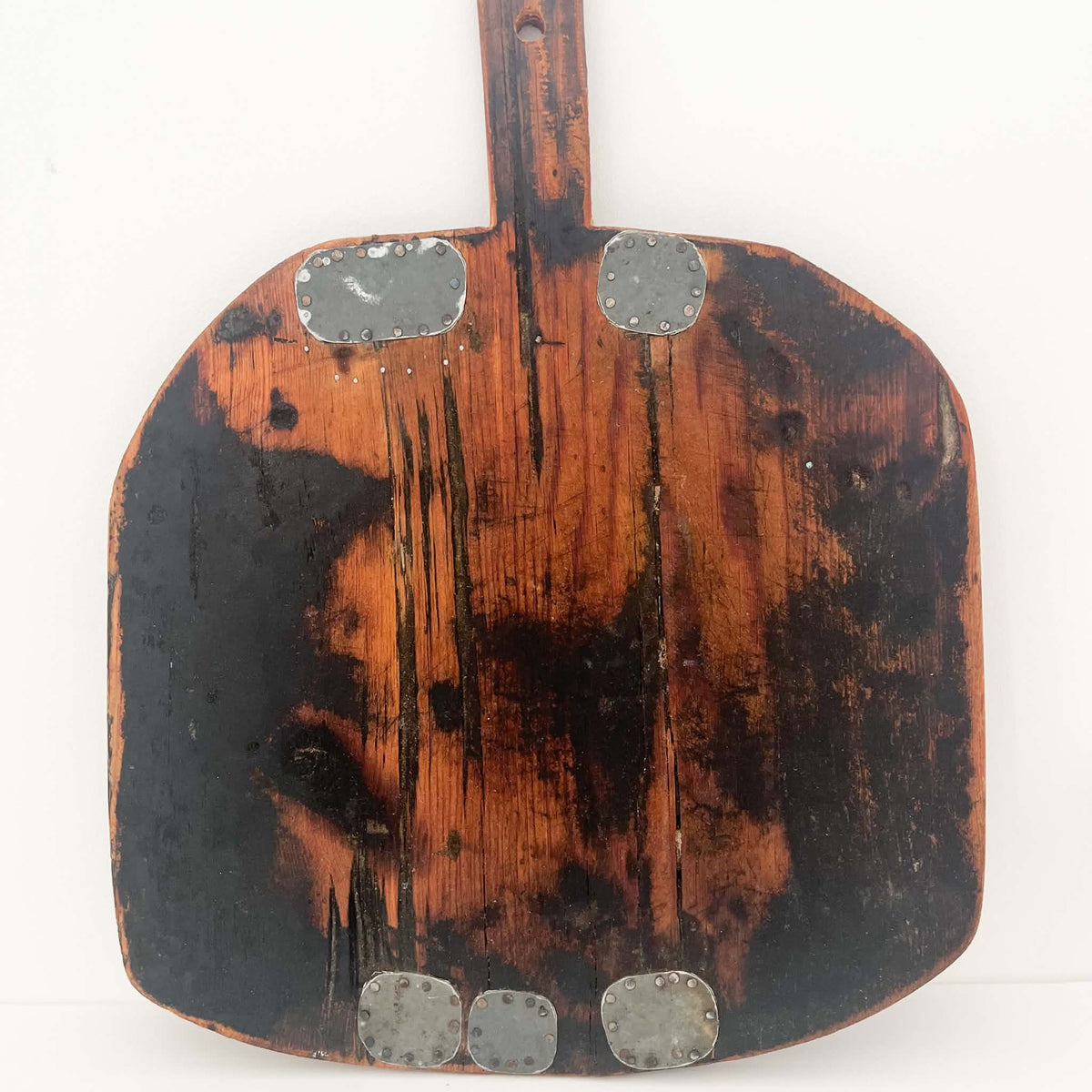 Rustic square wooden chopping board with softly rounded corners and a carved handle, full of authentic antique character