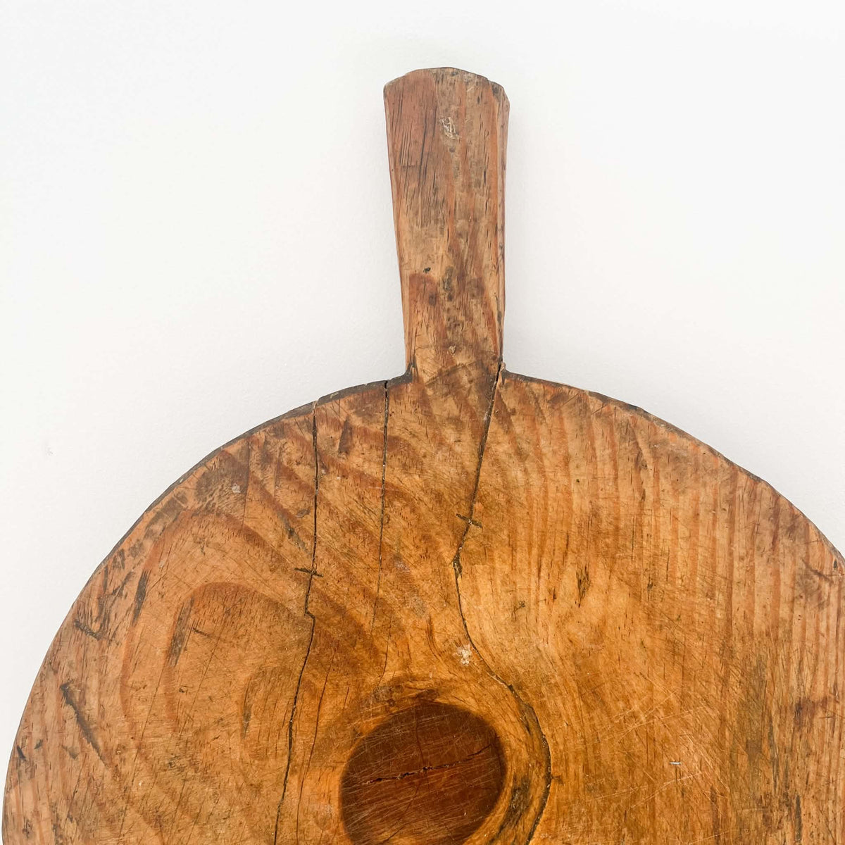 Vintage round wooden bread board with a hand-carved handle, ideal for rustic cottage and country kitchen styling.